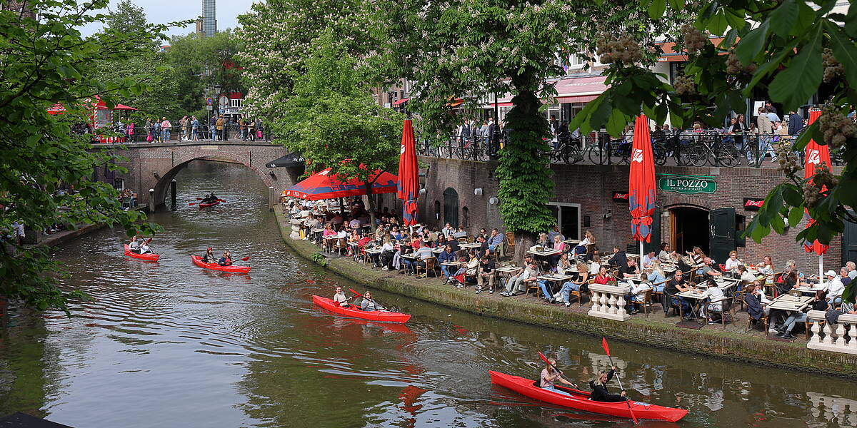 Link naar foto in Flickr: kanovaarders varen door de Oudegracht langs de volle terassen.